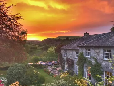 an image of a house with a sunset in the background at Pen-Y-Dyffryn Country Hotel in Oswestry