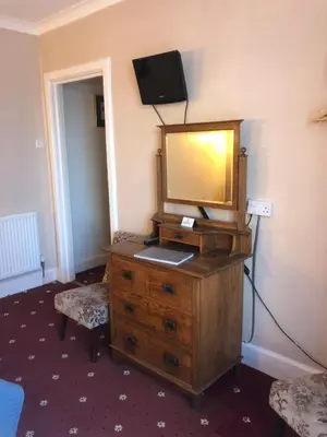 a room with a dresser with a mirror and a television at The Sandpiper in Barmouth