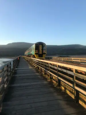 a train is crossing a bridge over a boardwalk at The Sandpiper in Barmouth