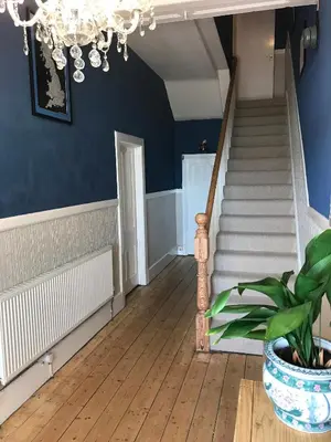 a staircase with blue walls and a chandelier at The Sandpiper in Barmouth