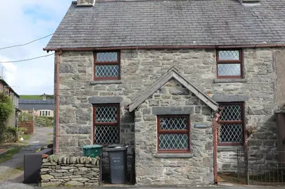 an old stone house with three windows and a trash can at Gwynfryn in Cerrig-y-Druidion