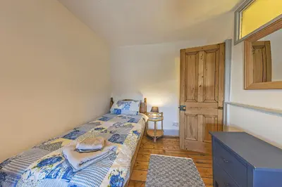 a small bedroom with a bed and a wooden floor at Gwynfryn in Cerrig-y-Druidion