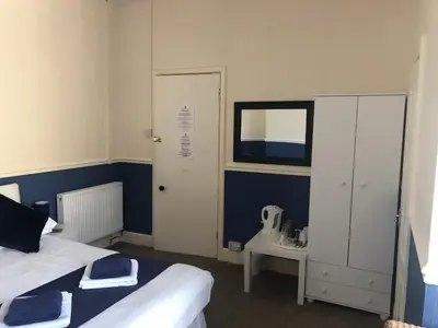 a bedroom with a bed and a cabinet and a mirror at Leamington House in Barmouth