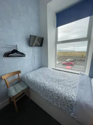 a bedroom with a bed and a window and a chair at Seascape in Barmouth