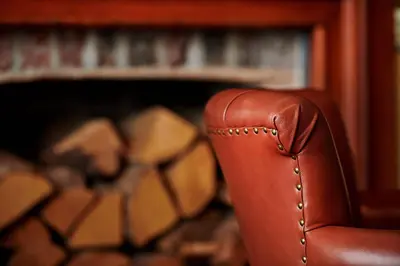 a brown leather chair sitting in front of a fireplace at The Glengower in Aberystwyth