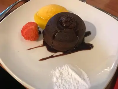 a white plate with a chocolate dessert and a strawberry at New Gurkha Inn in Brecon