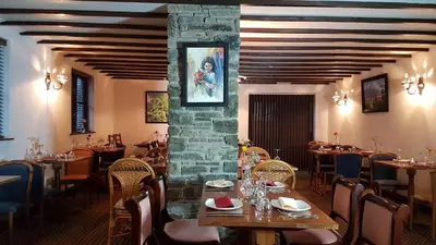 a restaurant with tables and chairs and a stone wall at New Gurkha Inn in Brecon