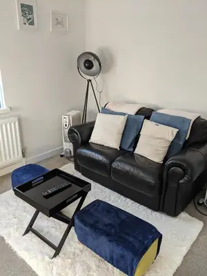 a living room with a black leather couch and a table at Hazler Lodge guest house in Church Stretton