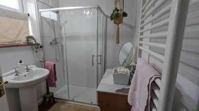 a white bathroom with a shower and a sink at Hazler Lodge guest house in Church Stretton
