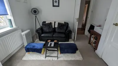 a living room with a black leather chair and a table at Hazler Lodge guest house in Church Stretton