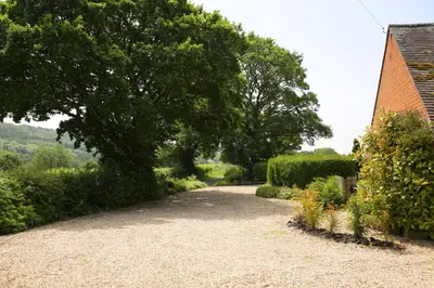 a gravel driveway with a tree and a house at Pheasant Walk at Eaton Manor in Church Stretton