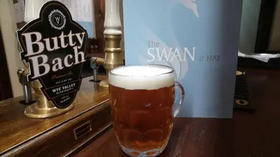 a glass of beer sitting on top of a bar at The Swan At Hay in Hay-on-Wye