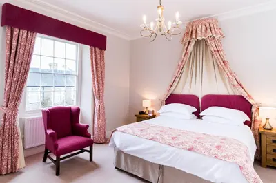 a bedroom with a canopy bed and a chair at The Swan At Hay in Hay-on-Wye