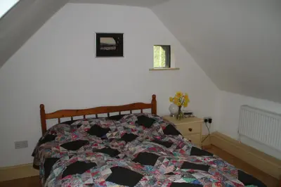 a bedroom with a bed with a quilt on it at Chestnut Cottage in Eardisley