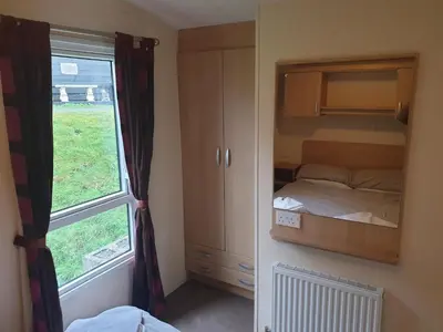 a small bedroom with a bed and a window at Sea retreat caravans in Aberystwyth