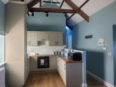 a kitchen with white cabinets and a blue wall at The Bakery in Llanddeiniol