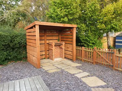 a wooden out house with a brick fireplace next to a fence at Ruth's Rest Country Retreat with private Hot Tub & Views of Open Countryside in Shrewsbury