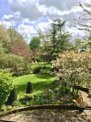a garden with flowers and trees on a lawn at Yew Tree Cottage in Leominster
