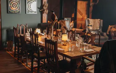 a wooden table with chairs and a long table with glasses on it at Palé Hall in Bala