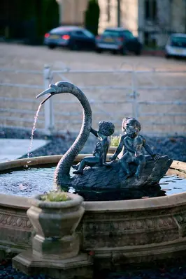 a statue of two children sitting in a fountain at Palé Hall in Bala