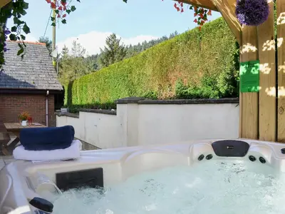 a jacuzzi tub with two chairs in a backyard at Dyffryn Haidd in Llanafan