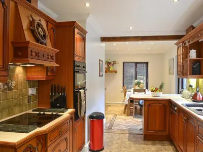 a kitchen with wooden cabinets and a dining room at Dyffryn Haidd in Llanafan