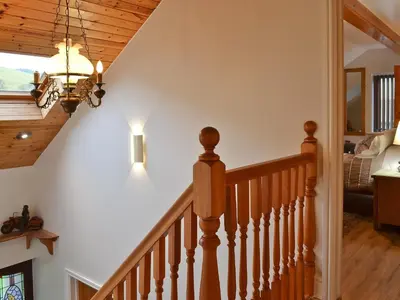 a staircase in a house with a chandelier at Dyffryn Haidd in Llanafan