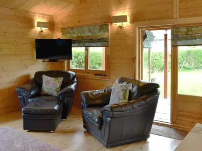 two leather chairs and a television in a room at Ty Pren in Dyffryn