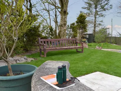 a bottle sitting on a table next to a bench at Bryntrisant in Devils Bridge