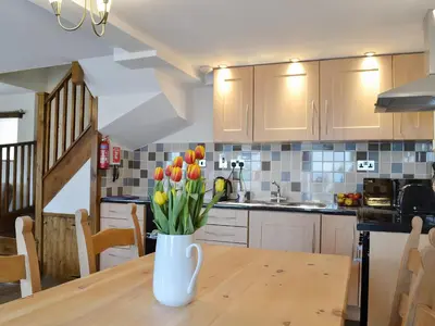 a vase of tulips on a wooden table in a kitchen at Bryntrisant in Devils Bridge