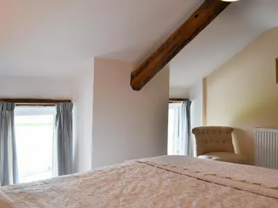 a bedroom with a bed and a chair and windows at Bryntrisant in Devils Bridge
