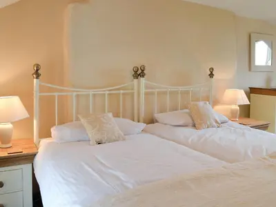 a bedroom with two beds with white sheets and pillows at Bryntrisant in Devils Bridge