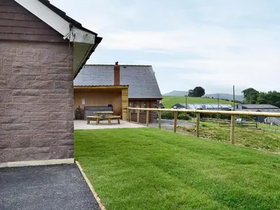 a backyard of a house with a bench and grass at Dolview in Penybont