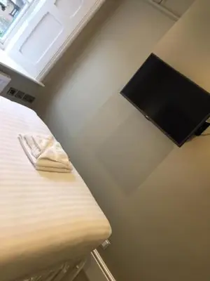 a room with a bed with a flat screen tv on the wall at Llys yr Onnen in Aberystwyth