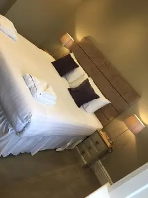 a bedroom with a bed with white sheets and pillows at Llys yr Onnen in Aberystwyth