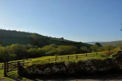 a fence in a field with a train on a hill at Barn Cottage in Brecon