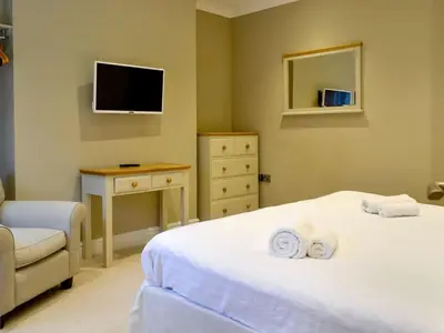 a bedroom with two beds and a tv and a chair at Llys Celyn - Holly Farm in Aberystwyth