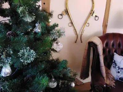 a christmas tree in a living room next to a couch at The Barn at Titley in Kington