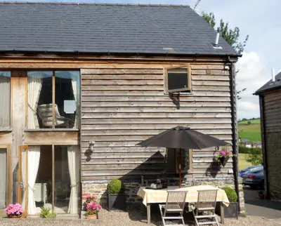 a table with an umbrella in front of a house at The Barn at Titley in Kington