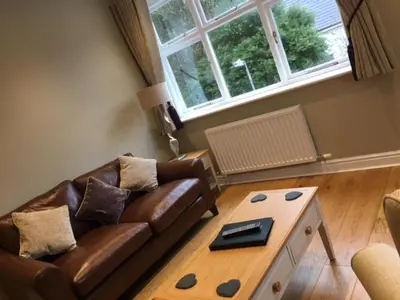 a living room with a couch and a coffee table at Llys y Dderwen - Oak Court in Aberystwyth