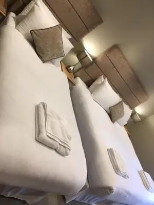 two beds in a hotel room with white pillows at Llys y Dderwen - Oak Court in Aberystwyth