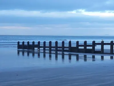 a pier on the beach with the ocean in the background at Pant Glas Barn in Llanbrynmair
