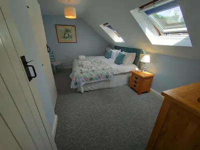a attic bedroom with a bed and a window at Pant Glas Barn in Llanbrynmair