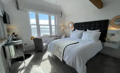 a bedroom with a large bed with a large window at Brig-y-Don in Aberdyfi