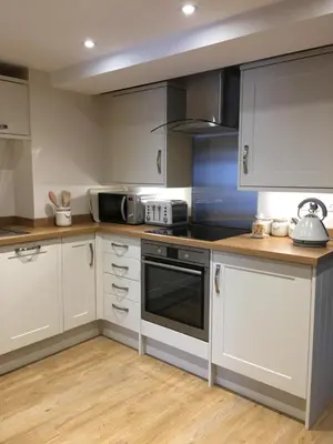 a kitchen with white cabinets and black appliances at Riverside Suites Llangollen in Llangollen