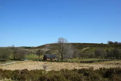 a house in a field with a hill in the background at LLanddewi Retreat in Llanddewi Ystradenny