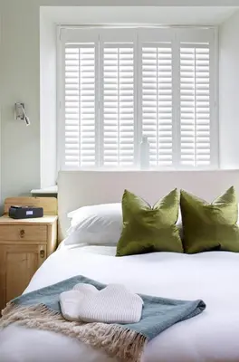 a bedroom with a white bed with green pillows at Cross Foxes - Bar Grill Rooms in Dolgellau