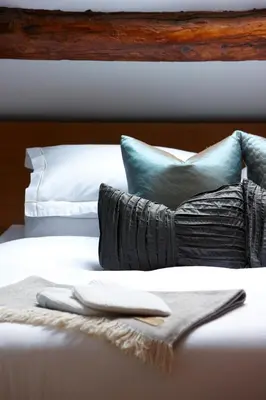 a white bed with blue pillows and a blanket at Cross Foxes - Bar Grill Rooms in Dolgellau
