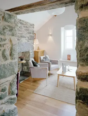 a living room with two chairs and a stone wall at Cross Foxes - Bar Grill Rooms in Dolgellau