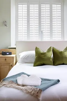 a bed with green pillows and a blanket on it at Cross Foxes - Bar Grill Rooms in Dolgellau